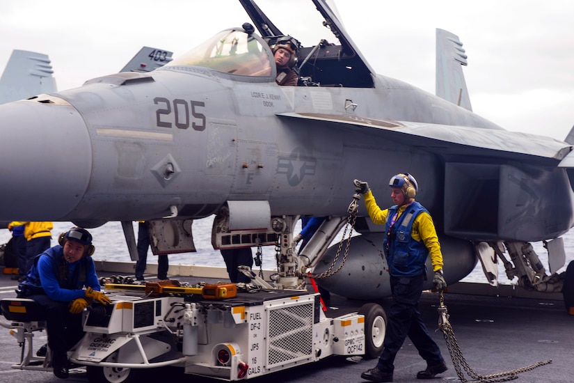 U.S. Navy Petty Officer 3rd Class Tom Xue, U.S. Navy Seaman James Ketler and U.S. Navy Petty Officer 3rd Class Ryan Stephenson move an F/A-18E Super Hornet from the Strike Fighter Squadron 14 into the hangar bay of the aircraft carrier USS John C. Stennis in the Pacific Ocean, Dec. 10, 2014. Xue is an aviation boatswain's mate handling, Ketler is an aviation electrician's mate airman, and Ryan Stephenson is an aviation boatswain's mate handling.