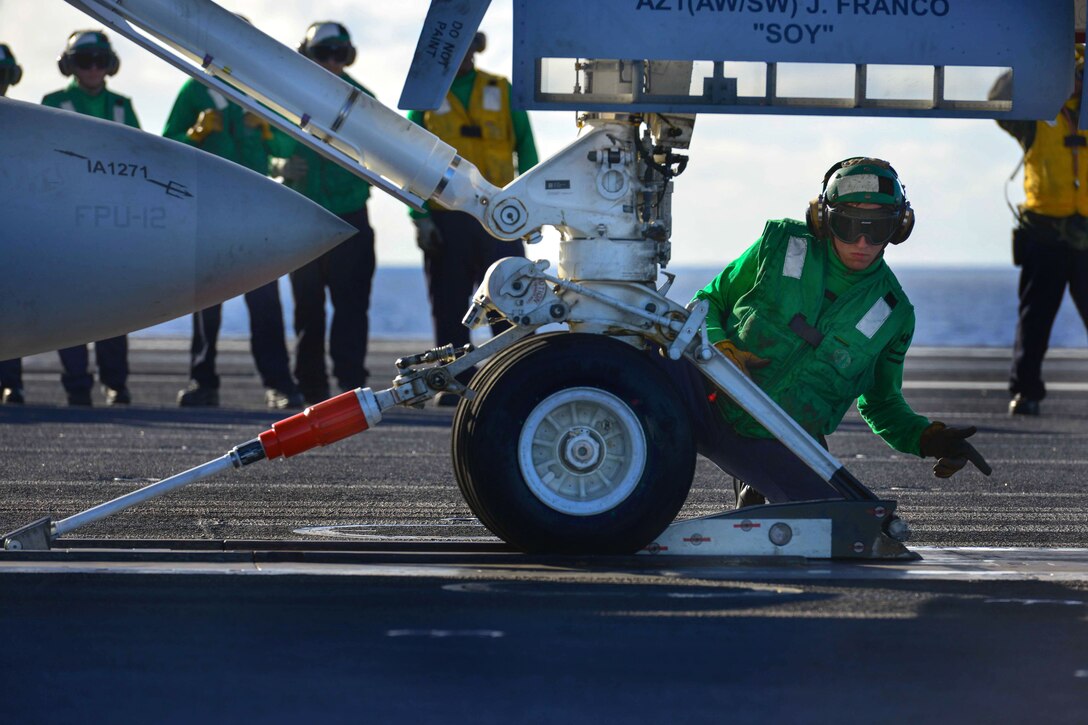 U.S. Navy Petty Officer 2nd Class Matthew Fulks loads an aircraft onto a catapult aboard the aircraft carrier USS John C. Stennis in the Pacific Ocean, Dec. 9, 2014. Fulks is an aviation boatswain's mate equipment.