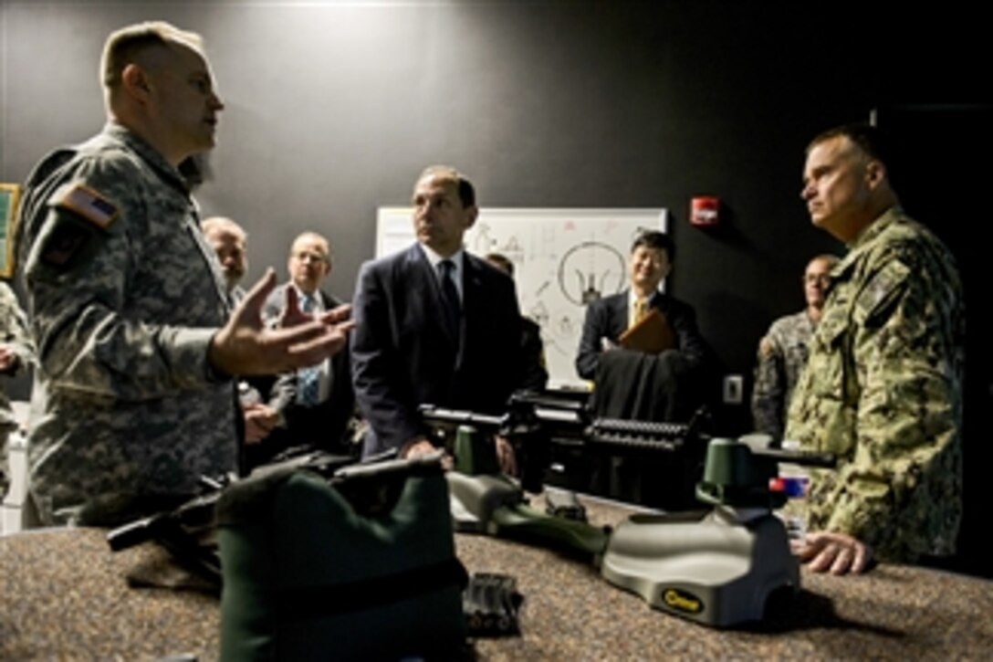 Navy Adm. James A. Winnefeld Jr., right, vice chairman of the Joint Chiefs of Staff, and Veterans Affairs Secretary Robert A. McDonald, center, receive a brief on a simulator for firearms training during a tour of the Center for the Intrepid in San Antonio, Dec. 19, 2014. Winnefeld brought McDonald, center professionals and researchers together to discuss innovative ways to improve the lives of wounded warriors. 