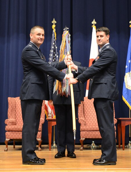 Col. Douglas DeLaMater, 374th Airlift Wing commander, left, gives command to Col. Robert Dotson, 374th Operations Group commander, during the 374 OG Change of Command Ceremony Dec. 19, 2014, at Yokota Air Base, Japan. The passing of the unit guidon is a time-honored military tradition representing the changing of command from one leader to another. (U.S. Air Force photo by Senior Airman Desiree Economides/Released)