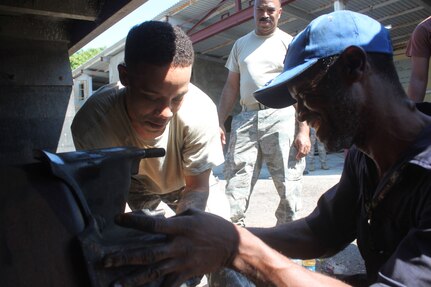 Sgt. Girard King, left, and Jamaican Defence Force civilian vehicle mechanic Dean Kemp, right, work on a 2.5-ton Jamaican Defence Force freightload truck while Senior Airman Renardo Butler, center, observes Dec. 10, 2014. King is a vehicle mechanic with the 273rd Military Police Co., D.C. National Guard, at Joint Base Anacostia-Bolling in Washington, and Butler is a vehicle mechanic from the 113th Wing, D.C. Air National Guard at Joint Base Andrews, Maryland. The D.C. National Guard Capital Guardians are participating in a subject matter expert exchange with the JDF under the National Guard Bureau’s State Partnership Program. 