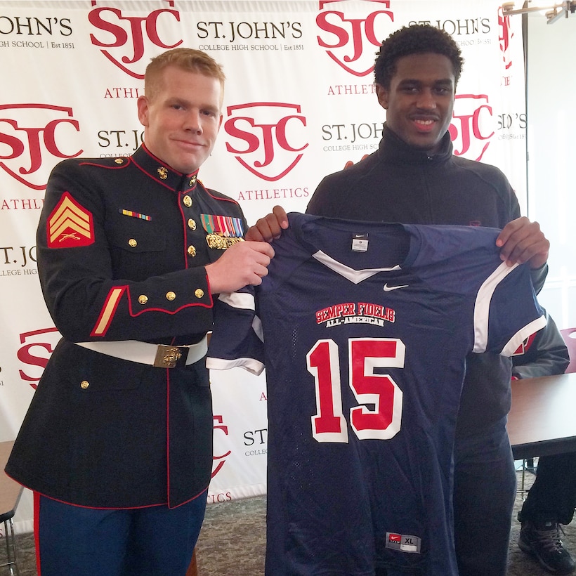 U.S. Marine Corps Sgt. Bryan Nygaard, the marketing and public affairs representative for Marine Corps Recruiting Station Baltimore, presents a jersey to Ayron Monroe at St. John’s College High School in Chevy Chase, Washington, D.C., December 17, 2014. Monroe, a defensive back for St. John’s College High School football team, has been selected to play in the 2015 Semper Fidelis All-American Bowl, which will be played in Carson, California Jan. 4, 2015.