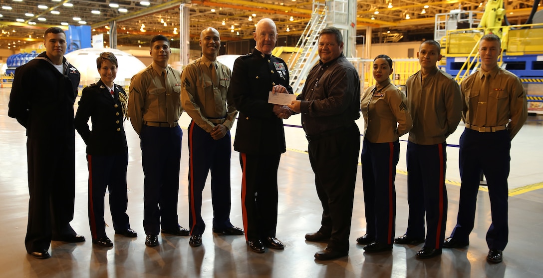 Lt. Gen. Richard P. Mills, commander of Marine Forces Reserve, receives a check from Bart Jones, general manager at Michoud Assembly Facility, Dec. 19, 2014, as a donation to the Marine Corps Reserve Toys for Tots foundation. Mills and fellow MARFORRES Marine and sailor volunteers went on a tour around the facility, seeing how the Space Launch System rocket is being made. (U.S. Marine Corps photo by Cpl. Brytani Musick)