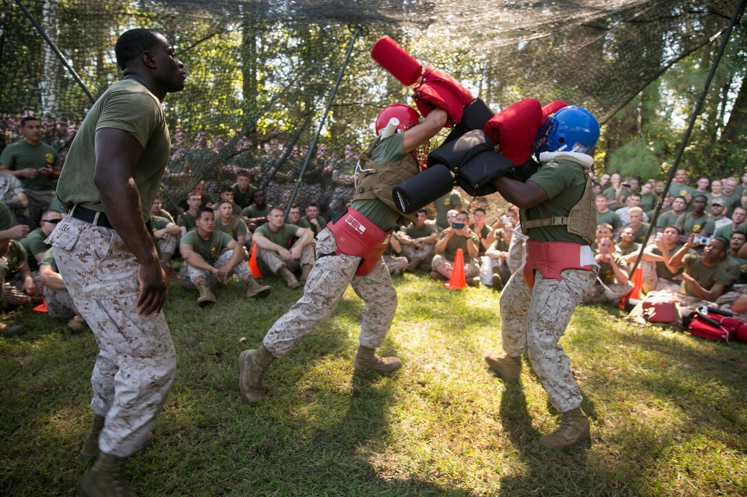 Cpl. Cameron Castillo, center, a satellite communications operator with 8th Communication Battalion, II Marine Expeditionary Force Headquarters Group, II Marine Expeditionary Force, attacks his opponent, Lance Cpl. Germale Springfield, an admin specialist with 2nd Air Naval Gunfire Liaison Company, II MHG, during the “Praetorian Challenge” field meet aboard Camp Lejeune, N.C., Oct. 10, 2014. During the challenge, the Marines participated in warrior events such as rock climbing, tire flipping, pulling a 7-ton truck, and tug-of-war. (U.S. Marine Corps photo by Cpl. Elizabeth A. Case/Released)