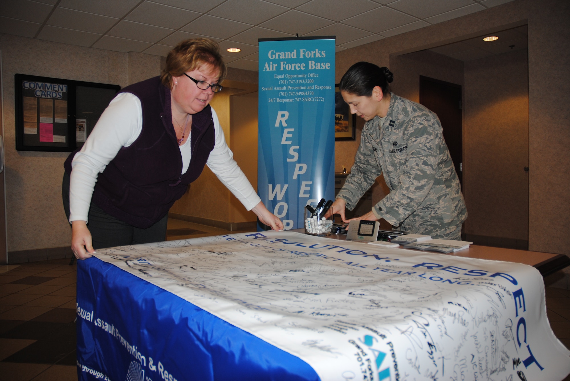 Sue Grollimund, 319th Air Base Wing Sexual Assault Prevention and Response Program assistant, and Capt. Shiela Flinders, 319th ABW Sexual Assault Response Coordinator set up their 2015 Year of Respect display, Dec. 18, 2014, at the Airey Dining Facility on Grand Forks Air Force Base, N.D.  The SAPR office promoted Resolution: Respect to more than 400 people from the base. (U.S. Air Force photo/Staff Sgt. Luis Loza Gutierrez)