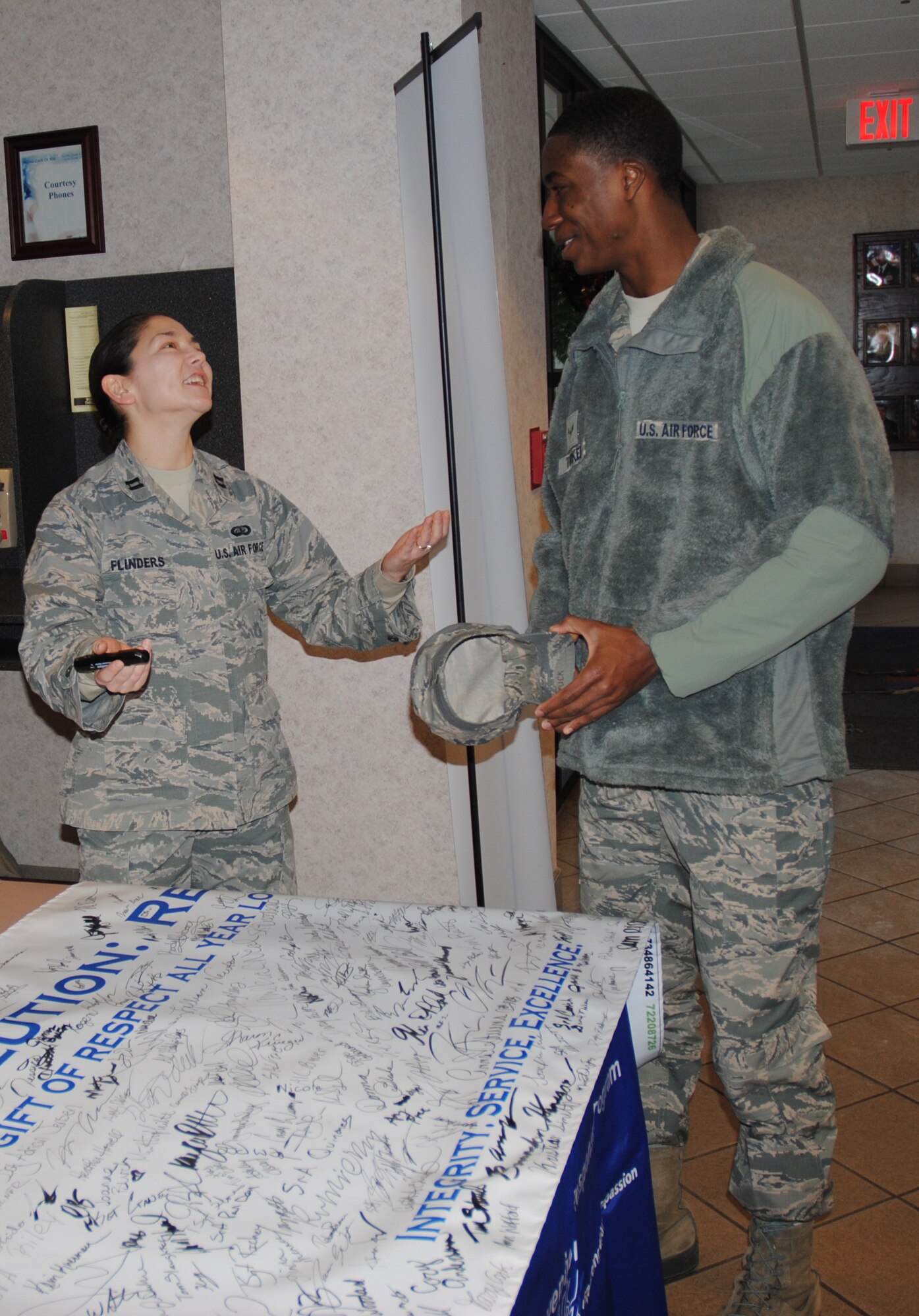 Capt. Shiela Flinders, 319th Air Base Wing Sexual Assault Response Coordinator, discusses the 2015 Year of Respect campaign with Airman 1st Class Samuel Tucker  Dec. 18, 2014, at the Airey Dining Facility on Grand Forks Air Force Base, N.D.  Airman Tucker and dozens of others were quick to sign the banner, pledging to make 2015 a year of respect. (U.S. Air Force photo/Staff Sgt. Luis Loza Gutierrez)