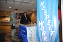 Sue Grollimund, 319th Air Base Wing Sexual Assault Prevention and Response Program assistant, helps Airman 1st Class Duane Alex, 319th Security Forces Squadron find a blank spot to sign his name to the 2015 Year of Respect banner, Dec. 18, 2014, at the Airey Dining Facility on Grand Forks Air Force Base, N.D.  From December 15 through19, the SAPR office took its “Resolution: Respect” campaign out to various base facilities. (U.S. Air Force photo/Staff Sgt. Luis Loza Gutierrez)