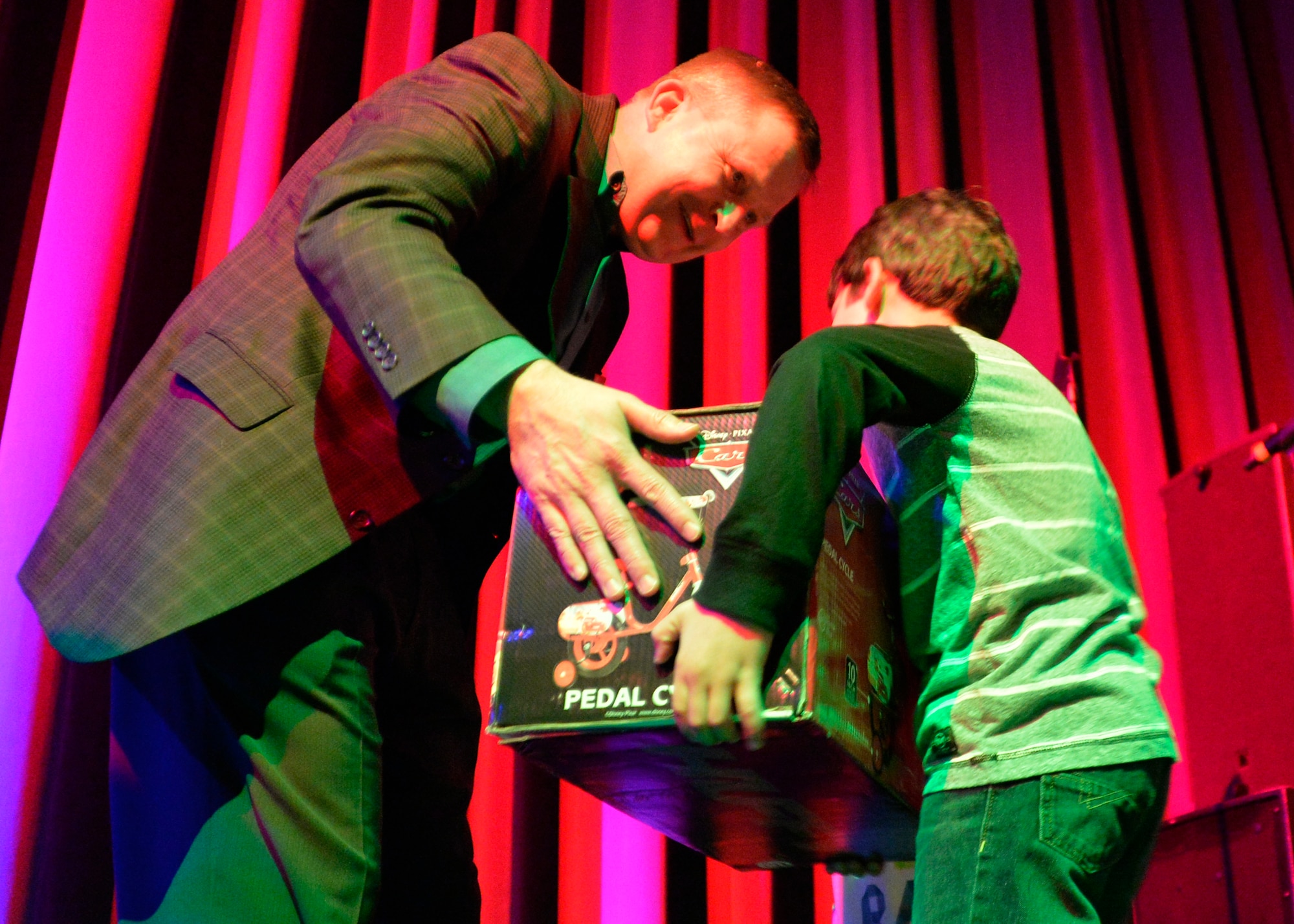 Col. James Cluff, 432nd Wing/432nd Air Expeditionary Wing commander, hands a child a raffle prize during a dinner for Creech and Nellis Air Force Base families Dec. 17, 2014, at the Aliante Casino and Hotel in Las Vegas. The event took place to recognize and build community between families of deployed members and allow them one-on-one time with commanders, first shirts, key spouses and other leadership. (U.S. Air Force photo by Staff Sgt. Adawn Kelsey/Released)