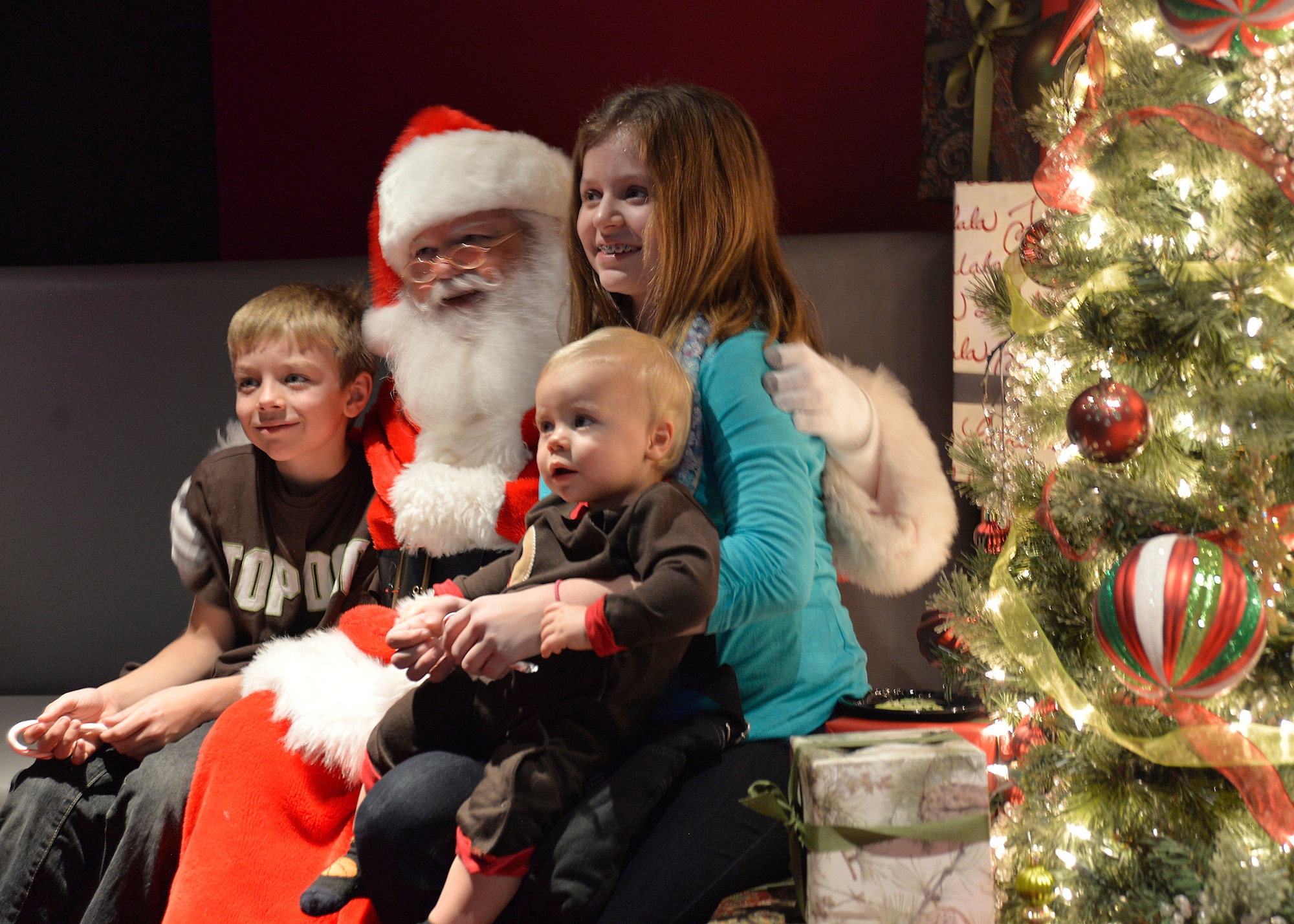 Alex Runquist, 8, left, his sister Ally, 12, and brother Aidan, 1, pose with Santa for a photo during a dinner for Creech and Nellis Air Force Base families Dec. 17, 2014, at the Aliante Casino and Hotel in Las Vegas. Families who attended the event enjoyed a dinner, raffle with prizes for children, and received a holiday care package. (U.S. Air Force photo by Staff Sgt. Adawn Kelsey/Released)