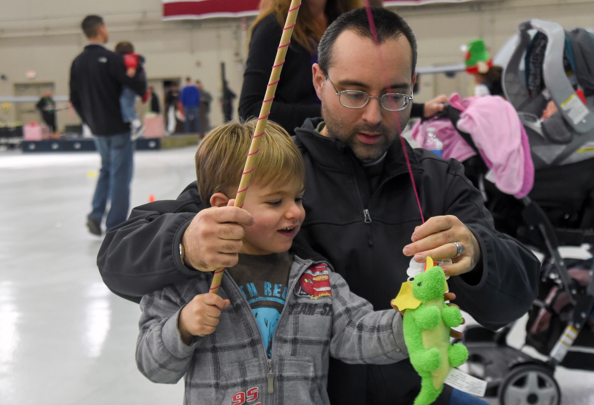 Master Sgt. Benjamin, 91st Attack Squadron sensor operator, helps his two-year-old son Lucas at a gift-fishing game during the 2014 Children’s Holiday Party at Creech Air Force Base, Nevada, Dec. 13, 2014. Nearly 100 children attended the annual event, which provided food, children’s games, crafts and a visit from Santa for military and civilian Air Force members and their families. (Last name has been removed for security purposes.) (U.S. Air Force photo by Tech. Sgt. Shad Eidson/Released)