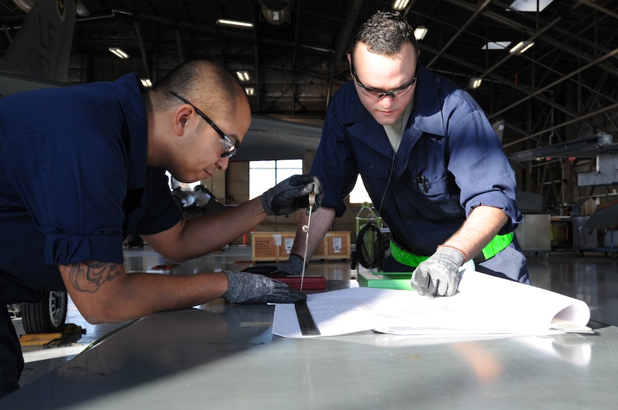 Staff Sgts. James Bacallo, left, and Joseph Gallegos, 309th Aircraft Maintenance Group Depot Structural Maintenance specialists, from Hill Air Force Base, Utah, analyze blueprints Dec. 11 for the canopy seal longeron repair in Hangar 914 at Luke Air Force Base. The CSL strap is responsible for enhancing the structural integrity of the aircraft. (U.S. Air Force photo/Staff Sgt. Luther Mitchell Jr.)