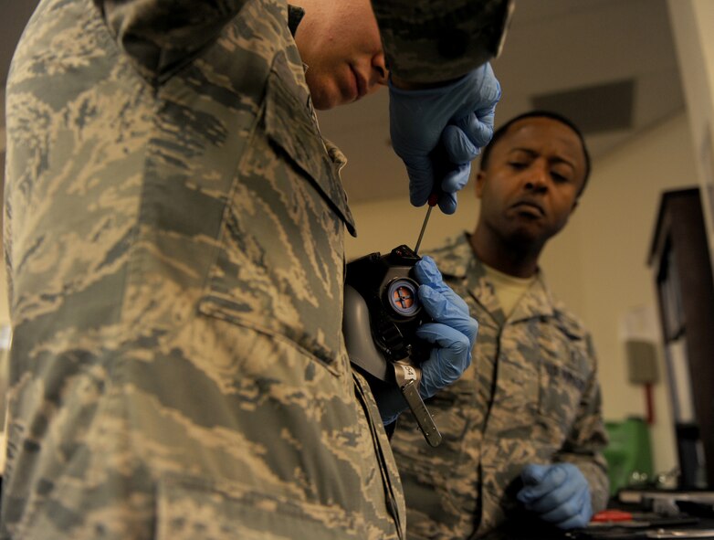 U.S. Air Force Chief Master Sgt. Eddie Webb, 7th Bomb Wing Command Chief, (right) watched as Airman Devon Azcuy, 7th Operation Support Squadron, disassembles a MBU-20P flight mask Oct. 20, 2014, at Dyess Air Force Base, Texas. Azcuy taught Webb how to disassemble, inspect, clean, and reassemble a HGU-55P flight helmet and a MBU-20P flight mask during the Teach the Chief program. (U.S. Air Force photo by Airman 1st Class Alexander Guerrero/Released)