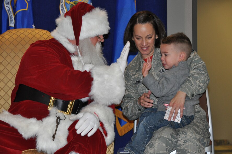 Santa Claus high-fives a service member's child during his visit to the Air Reserve Personnel Center Dec. 19, 2014, on Buckley Air Force Base, Colo. Brig. Gen. Samuel "Bo" Mahaney, ARPC commander, introduced Santa, Mrs. Claus and Sparkle the elf to excited families and children as he discussed the relationship with Santa Claus and the Air Force, which dates back decades. (U.S. Air Force photo/Tech. Sgt. Rob Hazelett)