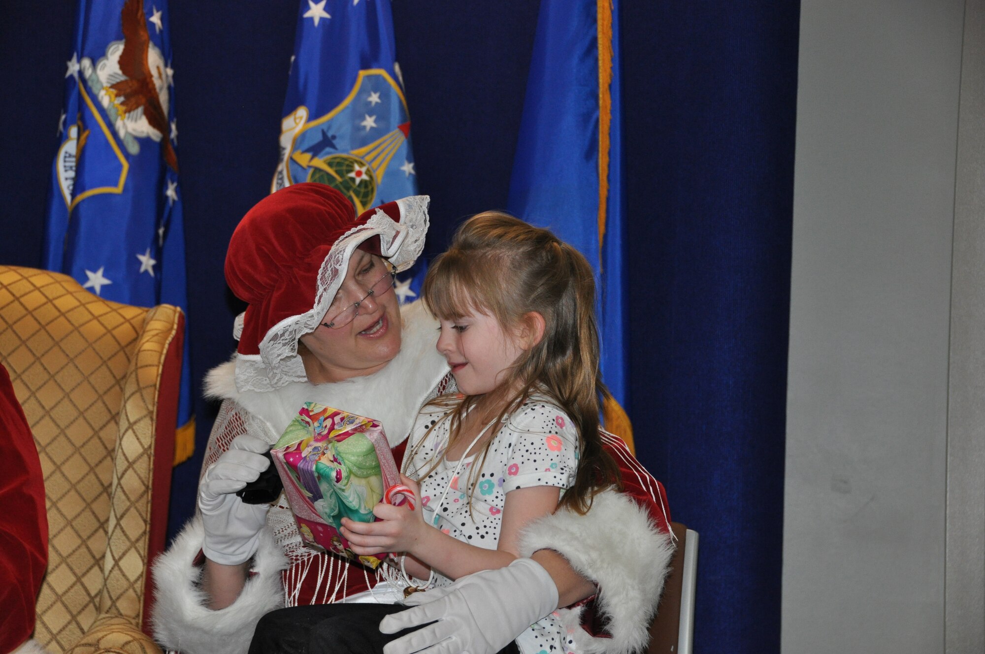 Mrs. Claus presents a child a gift during her visit to the Air Reserve Personnel Center Dec. 19, 2014, on Buckley Air Force Base, Colo. Brig. Gen. Samuel "Bo" Mahaney, ARPC commander, introduced Santa Claus, Mrs. Claus and Sparkle the elf to excited families and children as he discussed the relationship with Santa Claus and the Air Force, which dates back decades. (U.S. Air Force photo/Tech. Sgt. Rob Hazelett)