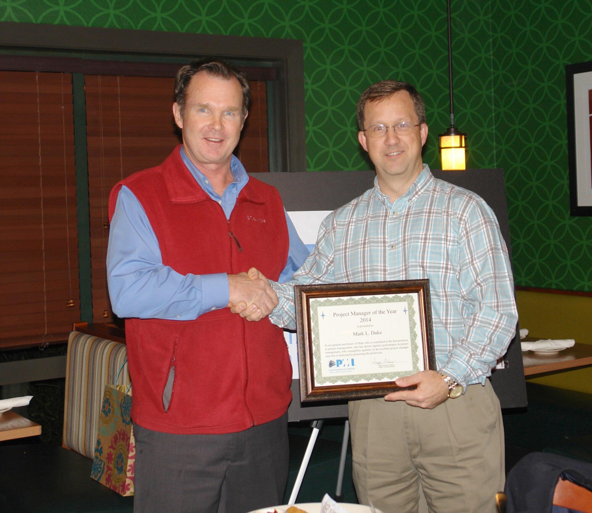 Mark Duke, pictured right, was selected as the 2014 Project Manager of the Year at the annual social for the Southern Middle Tennessee Branch of the Chattanooga Project Management Institute Chapter. Douglas Brown, left, ATA contract administrator and director of finance for the local PMI chapter, shakes Duke’s hand after presenting him the award. (Photo by Bob Lindeman)
