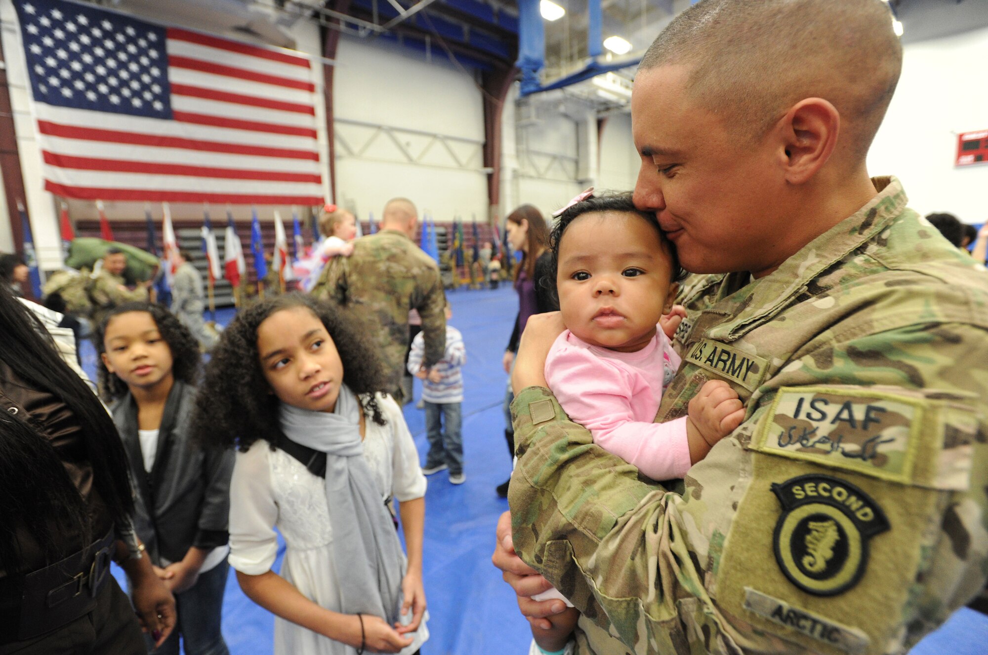 Army Sgt. Logan Gillespie, a native of Sebring, Fla., kisses his 4-month-old daughter Essence after the redeployment ceremony for the 109th Transportation Company, 17th Combat Sustainment Support Battalion, 2d Engineer Brigade, U.S. Army Alaska, at the Buckner Physical Fitness Center, Thursday, Jan. 30, 2014, on Joint Base Elmendorf-Richardson, Alaska, as his daughters Nina, 8, left, and Amyrrah, 11, watch.  The Muleskinners of the 109th Transportation Company deployed to Afghanistan in support of Operation Enduring Freedom in June 2013.  While there, they provided transportation and convoy security for military and host nation transportation assets. (U.S. Air Force photo by Justin Connaher/Released)