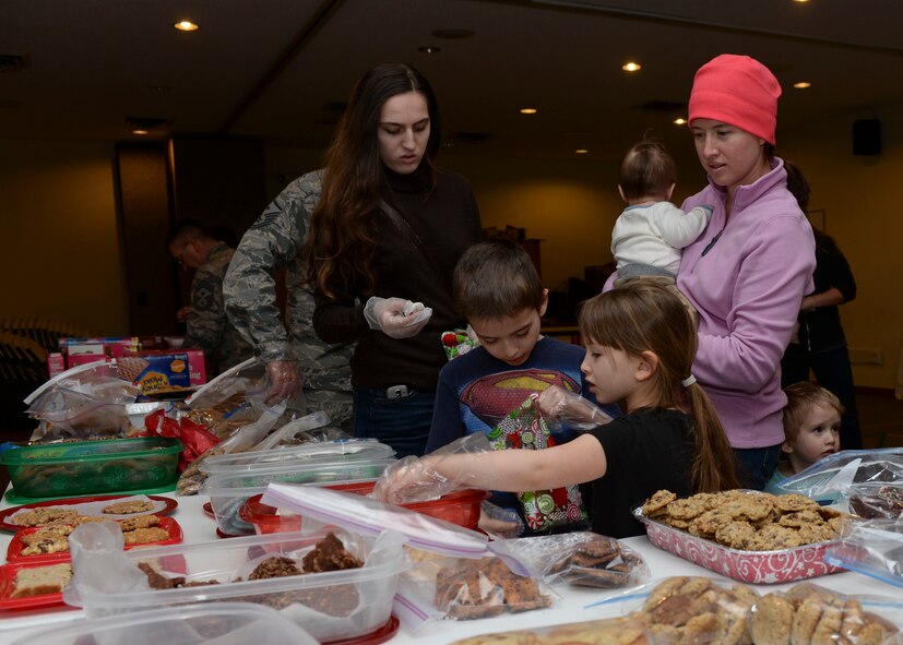 Airmen and volunteers from the Enlisted Spouses Club prepare treats during a holiday cookie drive in the Chapel Activities Center at Ellsworth Air Force Base, S.D., Dec. 15, 2014. More than 15 volunteers helped sort and bag the 4,000 donated cookies for Airmen residing in the dormitories. (U.S. Air Force photo by Senior Airman Anania Tekurio/Released) 