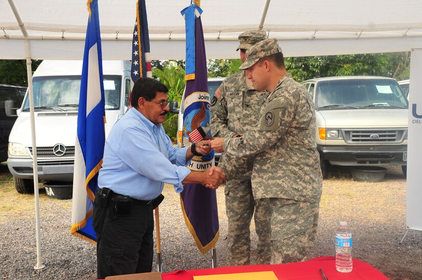 COPECO deputy commissioner Carlos Suarez accepts a key to one of the transfered vehicles from JTF-Bravo director of operations U.S. Army Lt. Col Joseph Leardi on Soto Cano Air Base, Honduras, Dec. 19, 2014.   The five vehicles were donated to COPECO by JTF-Bravo’s Defense Reutilization and Marketing Office on Soto Cano Air Base.  DRMO transferred the property to the U.S. Agency for International Development, which in turn worked together with JTF-Bravo and ASA to donate the goods to COPECO, an organization dedicated to organizing and coordinating preventive measures and participatory efforts to protect life, property and the environment of the people of Honduras.  (U.S. Air Force photo /Capt. Connie Dillon)