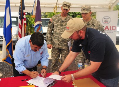 Carlos Suarez, COPECO deputy commissioner, signs papers that officially transfers the vehicles from USAID to COPECO on Soto Cano Air Base, Honduras, Dec. 19, 2014.  Five vehicles were donated to COPECO by JTF-Bravo’s Defense Reutilization and Marketing Office on Soto Cano Air Base.  DRMO transferred the property to the U.S. Agency for International Development, which in turn worked together with JTF-Bravo and ASA to donate the goods to COPECO, an organization dedicated to organizing and coordinating preventive measures and participatory efforts to protect life, property and the environment of the people of Honduras.  (U.S. Air Force photo /Capt. Connie Dillon)