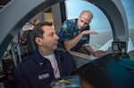 Kevin Coleman (right), 12th Operations Support Squadron flight simulator instructor, instructs Brazilian air force Maj. Gen. Ricardo Magalhaes, defense and air attaché, on flying in a T-6 simulator Dec. 11, 2014 during a visit to the 435th Flying Training Squadron at Joint Base San Antonio-Randolph, Texas. The flight simulator creates a realistic environment for students to experience flying a plane. (U.S. Air Force photo by Johnny Saldivar) 
