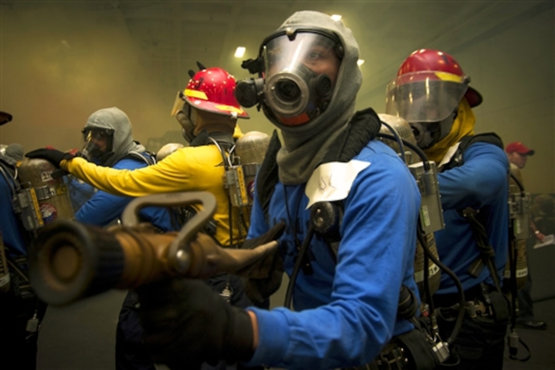 U.S. sailors man a hose during a general quarters drill aboard the aircraft carrier USS Carl Vinson in the Persian Gulf, Dec. 19, 2014.