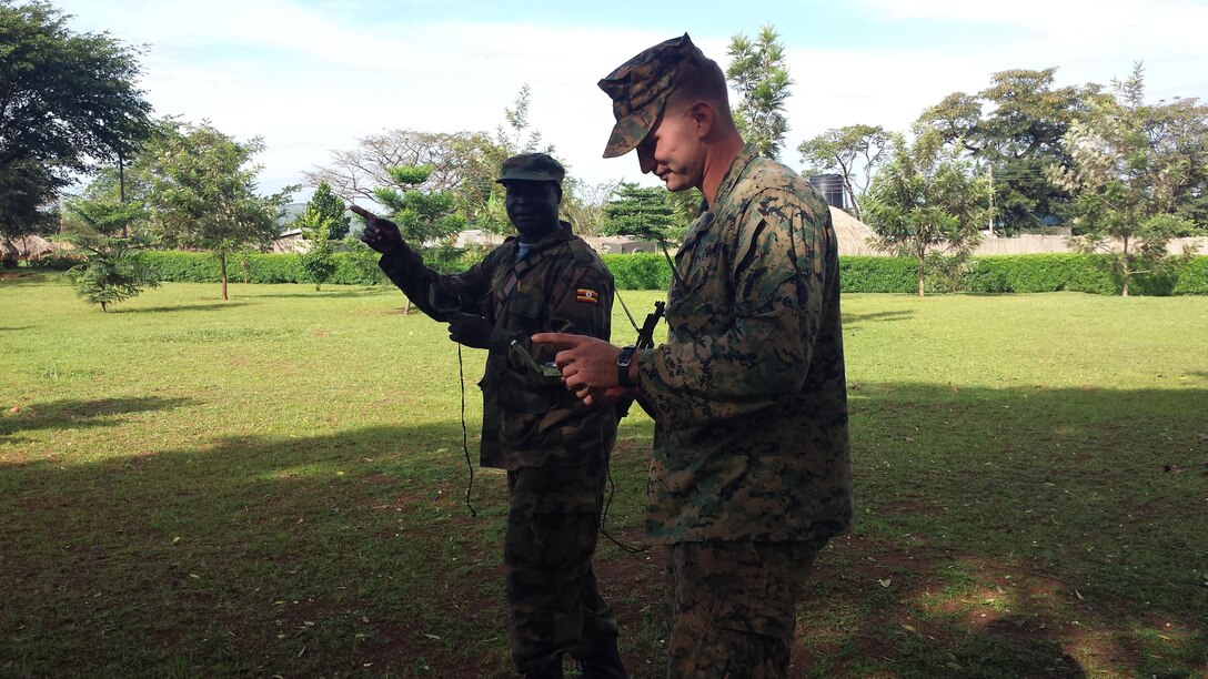 Sergeant David Borges assists a soldier from the Ugandan People’s Defense Force while doing land navigation in Camp Singo, Uganda, Dec. 10, 2014. Borges is part of a team of Marines and Sailors with SPMAGTF Crisis Response-Africa who were in Uganda from Oct. - Dec., training with the UPDF, focusing on infantry tactics, countering IEDs, and logistics. The Marines and Sailors conducting training in Uganda gained a better understanding and appreciation for the culture of the people of Uganda and the UPDF. (Courtesy Photo)