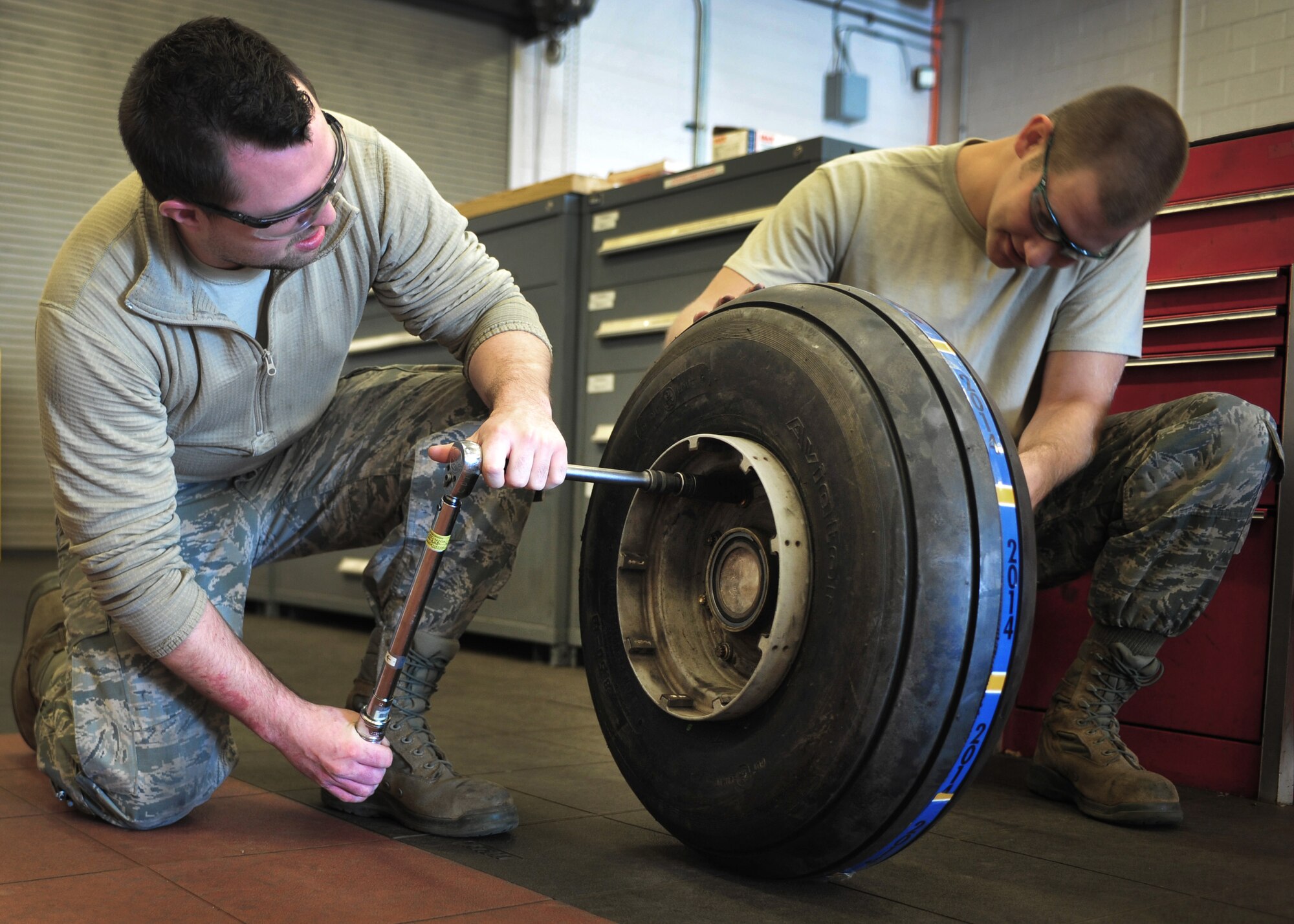 Two maintainers with the 27th Special Operations Maintenance Squadron work together to tighten bolts on a tire Dec. 18, 2014 at Cannon Air Force Base, N.M. The 27 SOMXS deploys personnel and specialized equipment to provide logistics support for the AC-130H, AC-130W, MC-130J, CV-22, MQ-1 and MQ-9 aircraft. (U.S. Air Force photo/Senior Airman Eboni Reece)
