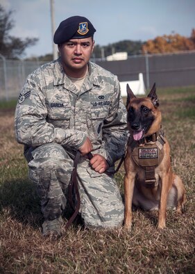 Senior Airman George Garcia, 8th Security Forces Squadron military working dog handler, poses for a photo with his MWD at Kunsan Air Base, Republic of Korea, Nov. 14, 2014. Garcia was recognized by Col. Kenneth “Wolf” Ekman, 8th Fighter Wing commander, as the top performer of the week. (U.S. Air Force photo by Senior Airman Taylor Curry/Released)  