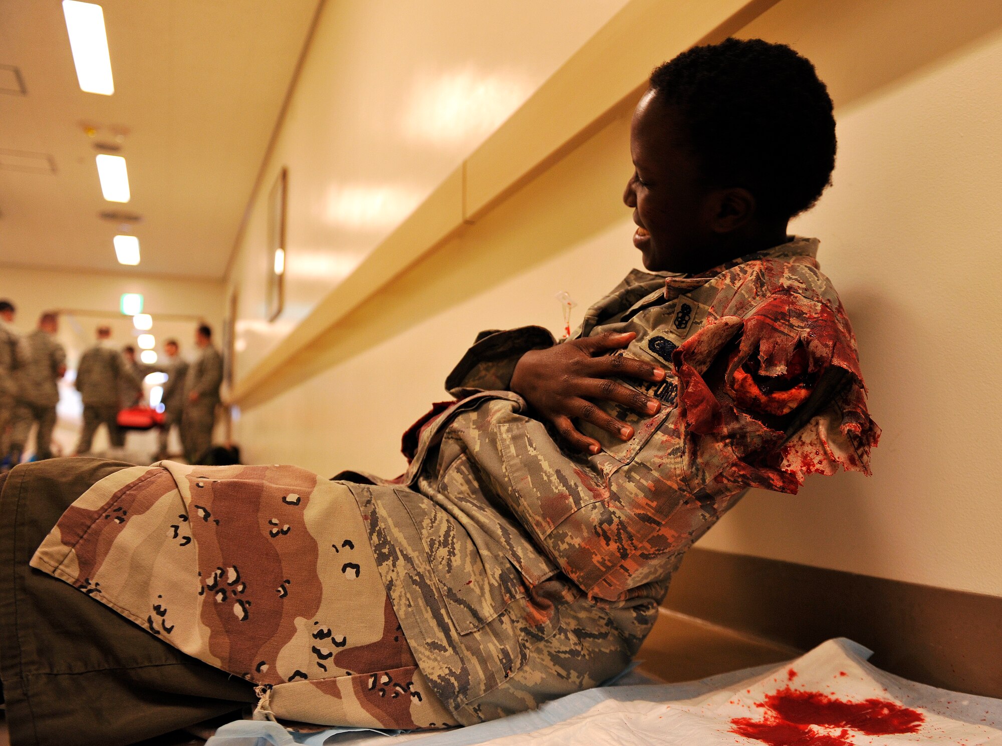 U.S. Air Force Senior Airman Anneth Moses, 18th Medical Operations Squadron medical technician a simulated accident victim, grimaces in pain during disaster team training on Kadena Air Base, Japan, Dec. 18, 2014. Moses was a volunteer moulage victim for disaster team training to help add realism to the triage process. (U.S. Air Force photo by Naoto Anazawa)