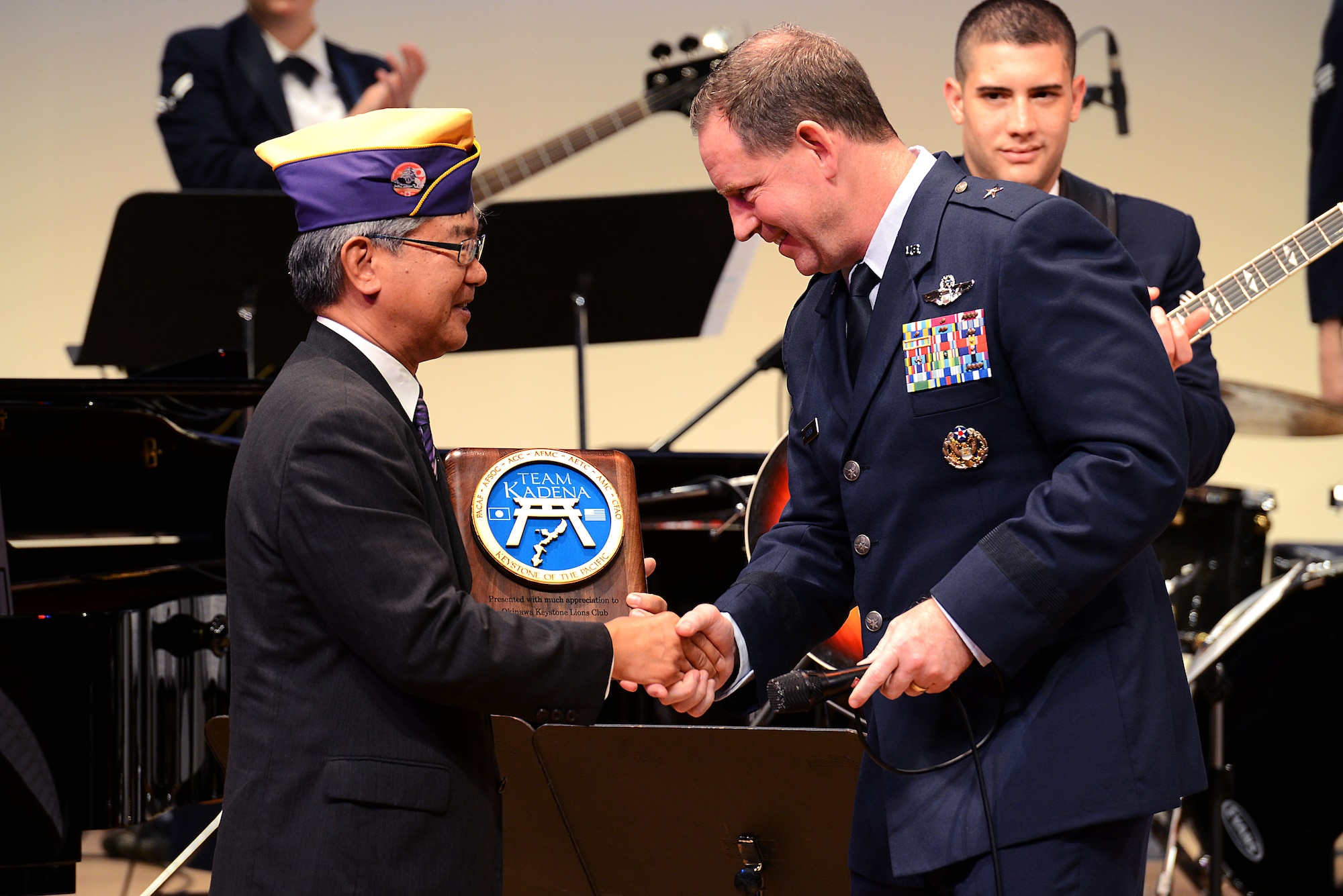U.S. Air Force Brig. Gen. James Hecker, 18th Wing commander, presents a token of appreciation to Eduardo Oyadomari, Okinawa Keystone Lion's Club president, following a friendship concert by the U.S. Air Force Band of the Pacific-Asia jazz ensemble in Naha, Japan, Dec. 11, 2014. The concert, which was sponsored by the club, was held as a means to show appreciation for the local community. (U.S. Air Force photo by Senior Airman Maeson L. Elleman)
