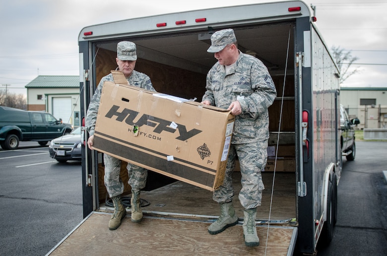 141217-Z-JU667-017: Chief Master Sgt. Ray Dawson (left), command chief master sergeant of the 123rd Airlift Wing, and Senior Master Sgt. Darryl Loafman, the wing’s ground safety manager, unload a child’s bike as part of Operation Military Cheer at the Kentucky Air National Guard Base in Louisville, Ky., on Dec. 17, 2014. The gifts, donated by the American Legion Auxiliary’s Anderson Unit 34 in Lawrenceburg, Kentucky, will be provided to the children of 11 Kentucky Air National Guard Airmen. (Kentucky Air National Guard photo by Master Sgt. Phil Speck)