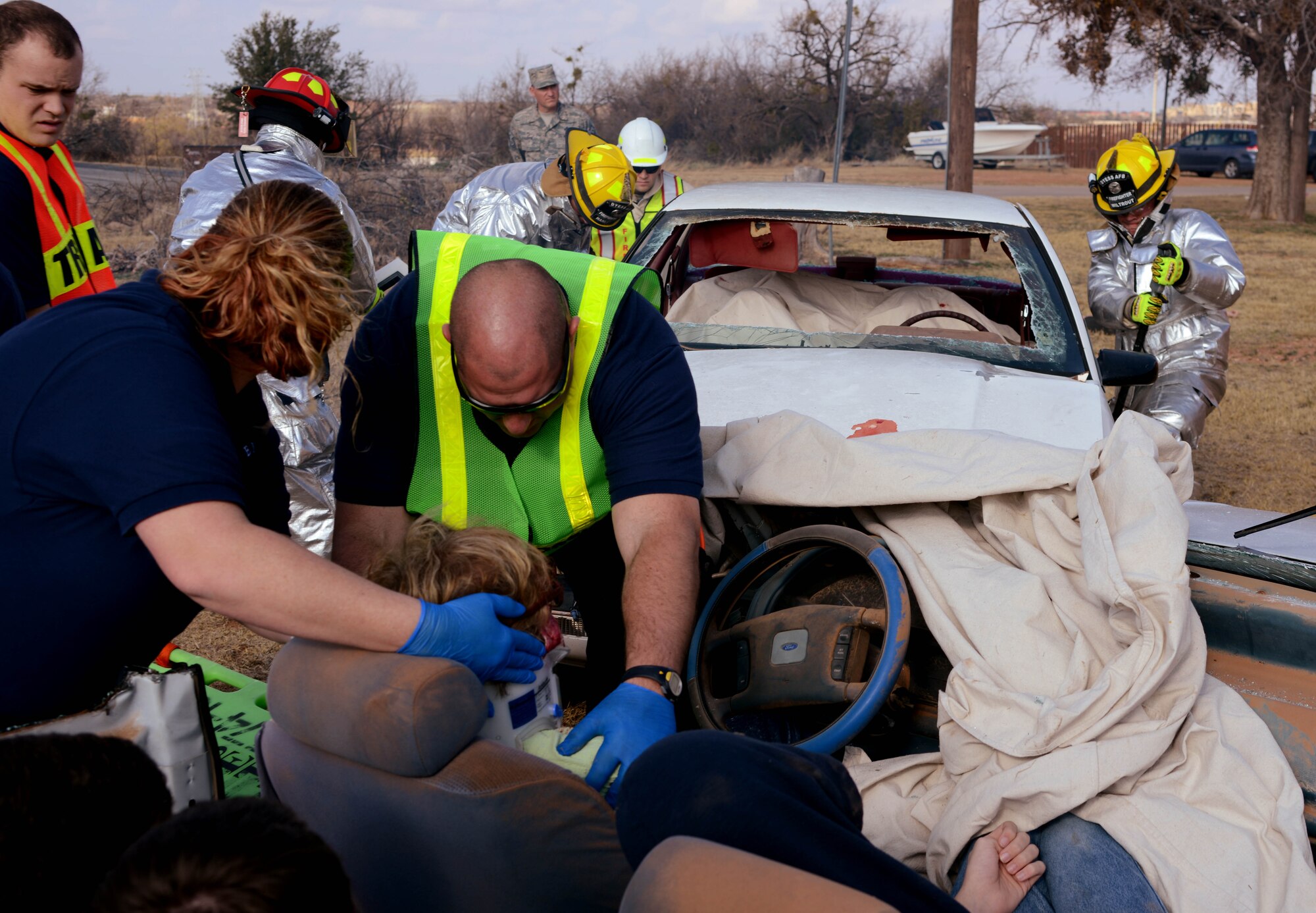 Students attending the Texas State Technical College emergency medical technician course practice stabilizing a victim’s neck as Dyess firefighter, from the 7th Civil Engineer Squadron remove doors from a vehicle Dec. 12, 2014, at Texas State Technical College in Abilene, Texas. The mass casualty exercise served as an opportunity for Dyess firefighters to train as a team, while coordinating with local emergency medical teams they work with during real-world events. (U.S. Air Force photo by Senior Airman Peter Thompson/Released)