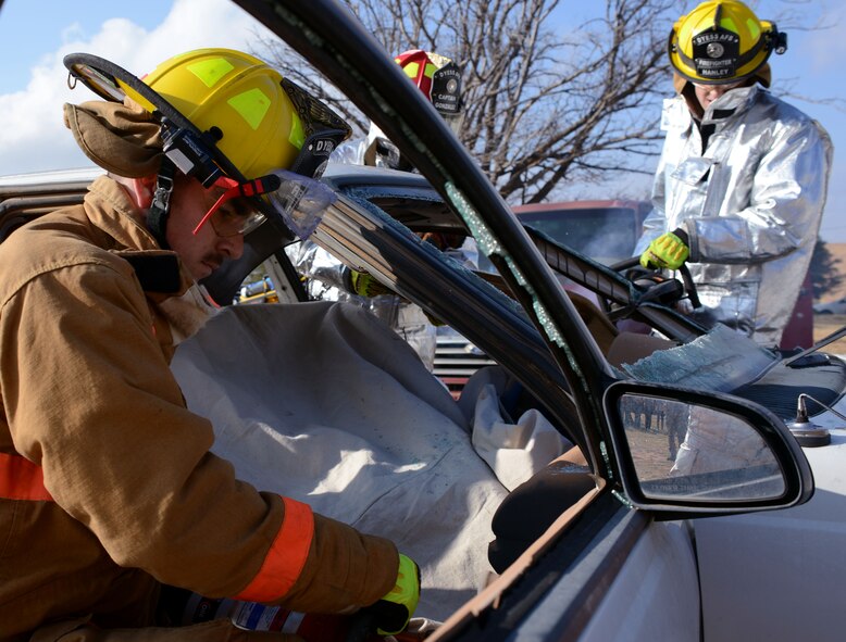 Dyess firefighters from the 7th Civil Engineer Squadron remove windows and doors from a vehicle Dec. 12, 2014, at Texas State Technical College in Abilene, Texas. The firefighters used their tools and knowledge of auto extrication to remove simulated patients from vehicles during a mass casualty exercise. (U.S. Air Force photo by Senior Airman Peter Thompson/Released)