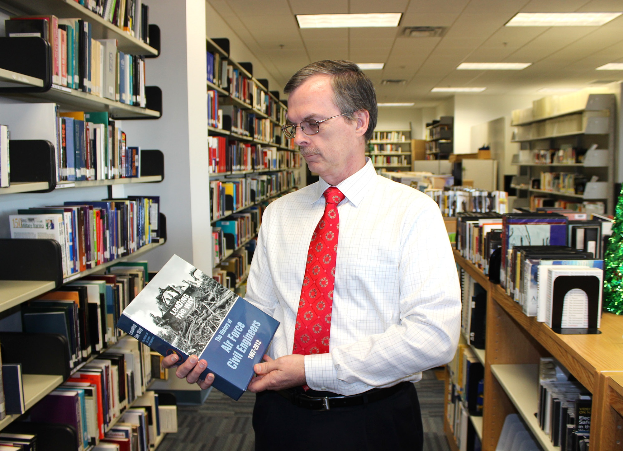 Dr. Ronald Hartzer, Air Force civil engineer historian at the Air Force Civil Engineer Center, examines a copy of his new book, Leading the Way: The History of Air Force Civil Engineers in AFCEC’s Technical Information Center at Tyndall Air Force Base, Florida. Leading the Way is the first comprehensive history of Air Force civil engineers, tracing the roots of the career field from aviation engineers in the Army Air Corps through World War II, Vietnam, Desert Storm and post 9-11 operations in Iraq and Afghanistan. (U.S. Air Force photo/John Burt/Released)