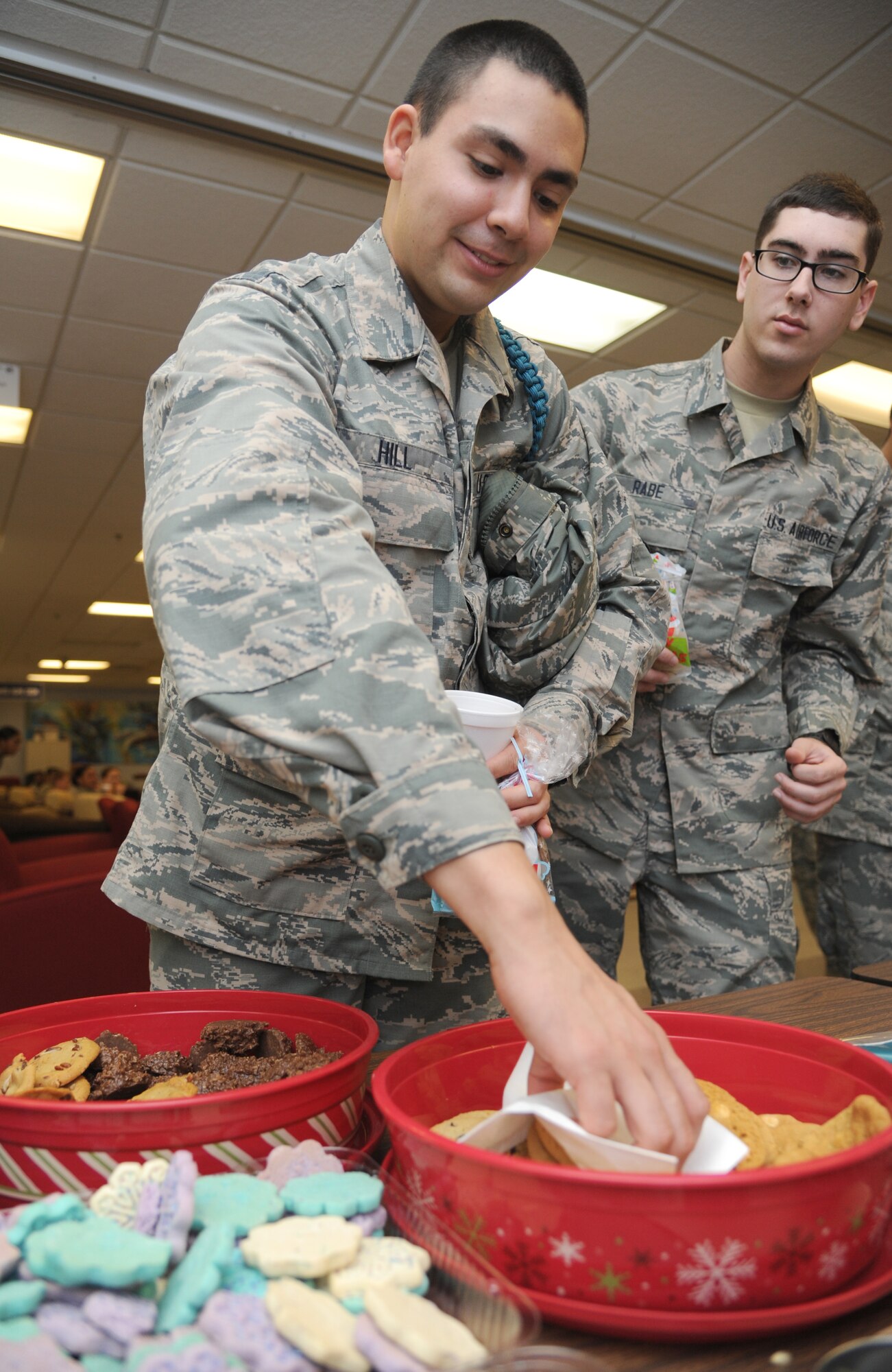 Airmen Basic Samuel Hill, 334th Training Squadron, and Michael Rabe, 336th Training Squadron, help themselves to cookies Dec. 23, 2014, at the Levitow Training support Facility, Keesler Air Force Base, Miss.  More than 200 bags of cookies, which were baked and packaged by 81st Training Group spouses, hot chocolate, coffee and popcorn were available for the Airmen that remained at Keesler over the holiday period.  The 81st Training Wing Chaplain staff hosted the event followed by the showing of Christmas movies.  (U.S. Air Force photo by Kemberly Groue)