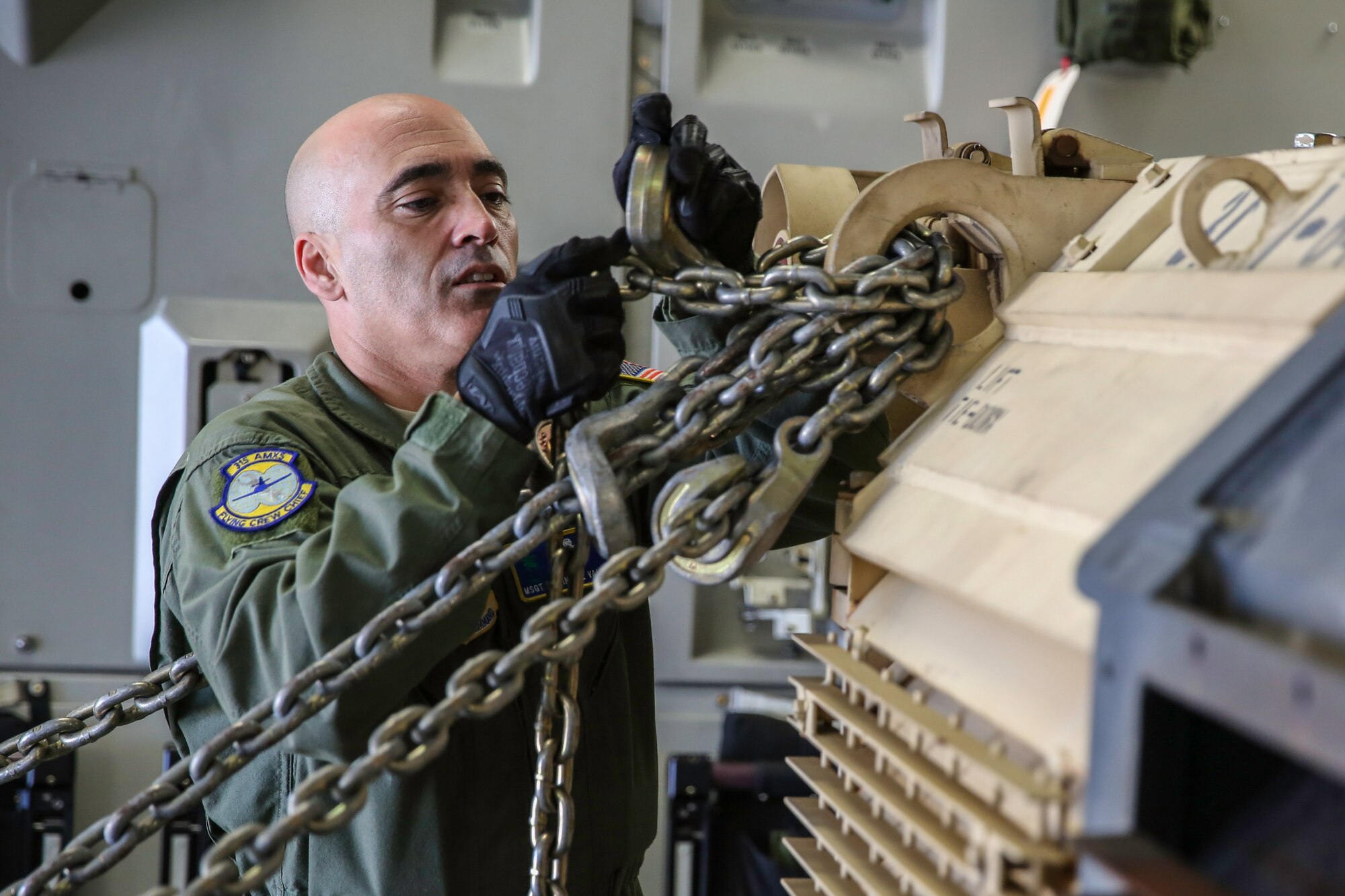 Master Sgt. Edwin Del Valle attaches a tie-down chain on a an Abrams M1A2 tank in the cargo compartment of a C-17 Globemaster III Dec. 11, 2014 at North Air Force Auxiliary Field in North, S.C. The tank movement was part of a two-day exercise which integrated C-17 air and ground crew training for 315th Airlift Wing Airmen stationed at Joint Base Charleston, S.C. as well as Soldiers from one of the 3rd Infantry Division’s Immediate Ready Companies stationed at Fort Stewart, Ga. Four C-17’s were used during the exercise to deploy and redeploy two Abrams M1A2 tanks, an M88 recovery vehicle and two M2A3 Bradley Fighting Vehicles. Del Valle is a flying crew chief at JBC. (U.S. Air Force photo by Tech. Sgt. Shane Ellis)