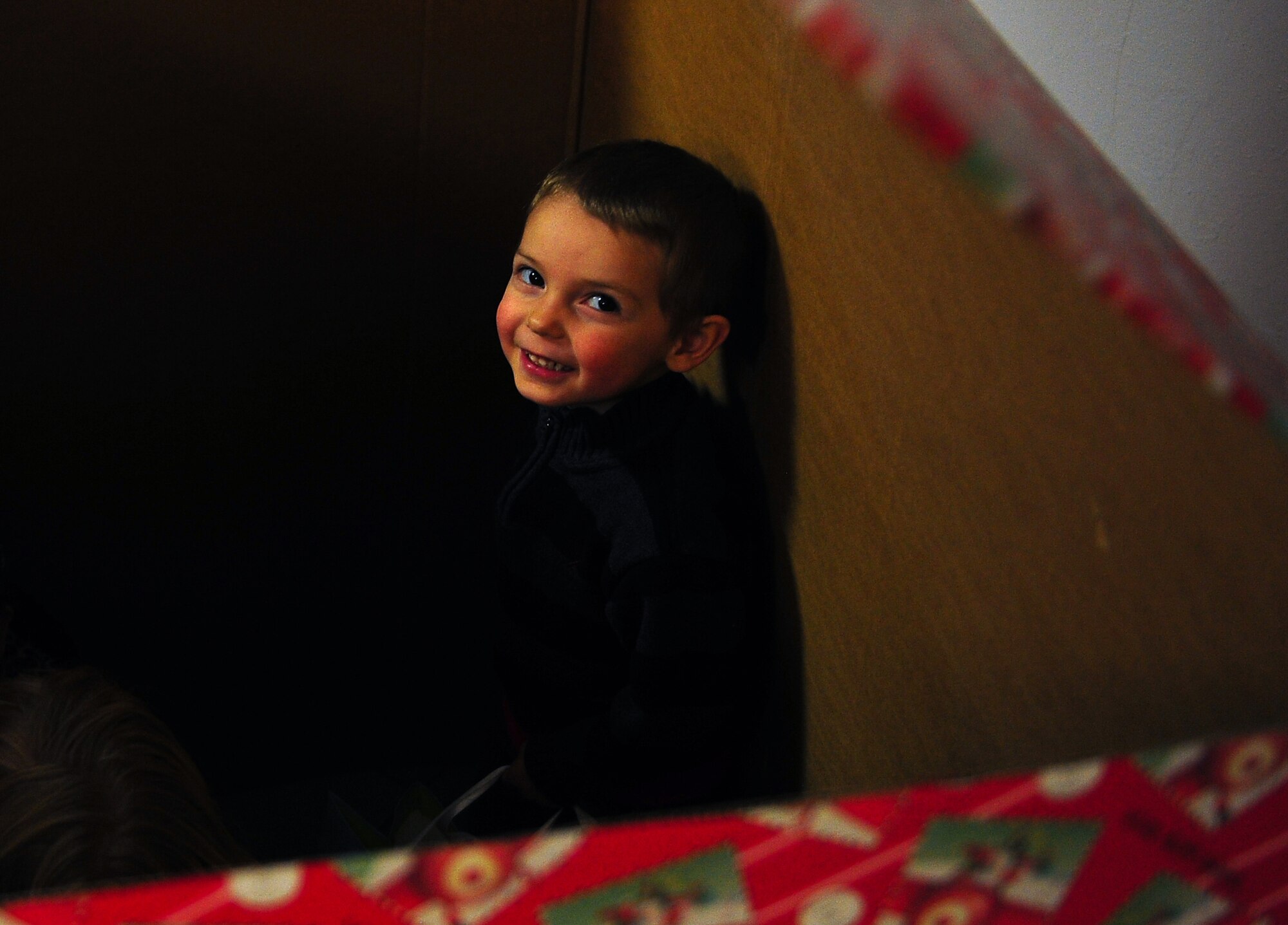 James Anderson plays in the gift-wrapped box his father, Staff Sgt. Richard Anderson, 37th Airlift Squadron loadmaster, jumped out of, surprising James and his sisters Rain and Faith on Dec. 23, 2014 at Ramstein Air Base Germany. Just like most children though, it doesn’t matter how great the gift is, eventually they’ll end up just playing with the box. (U.S. Air Force photo/Staff Sgt. Kris Levasseur)