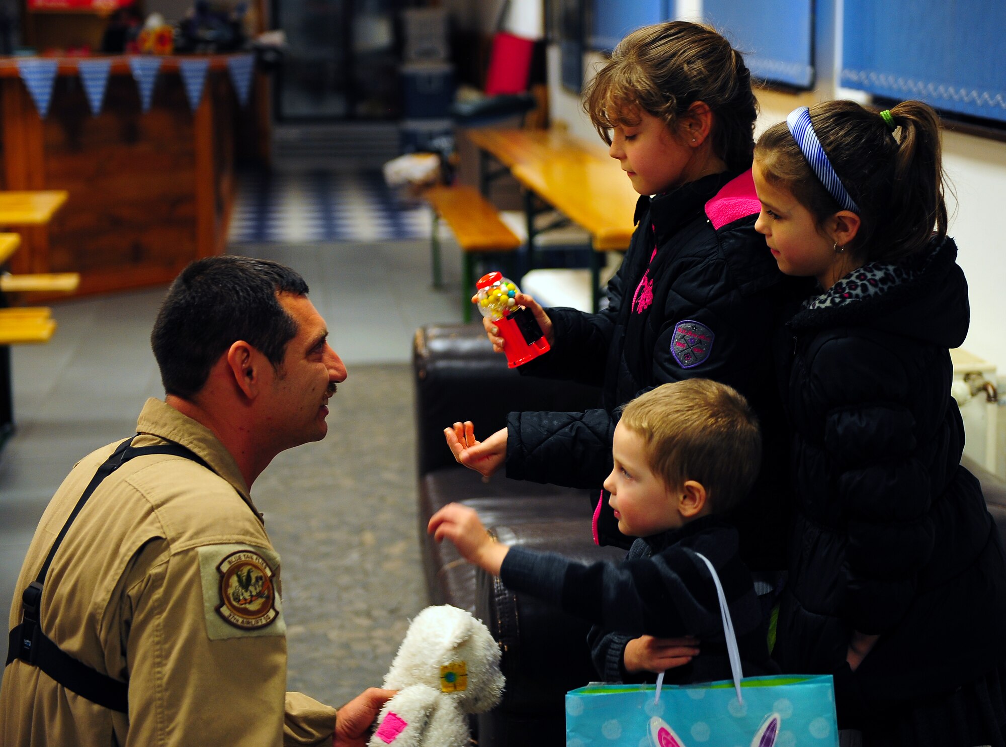 Rain, Faith and James Anderson show their father, Staff Sgt. Richard Anderson, 37th Airlift Squadron loadmaster, the gifts they brought for Airmen who couldn’t be with their families during the holidays Dec. 23, 2014 at Ramstein Air Base, Germany. The children were not expecting their father home until after the holidays. (U.S. Air Force photo/Staff Sgt. Kris Levasseur)