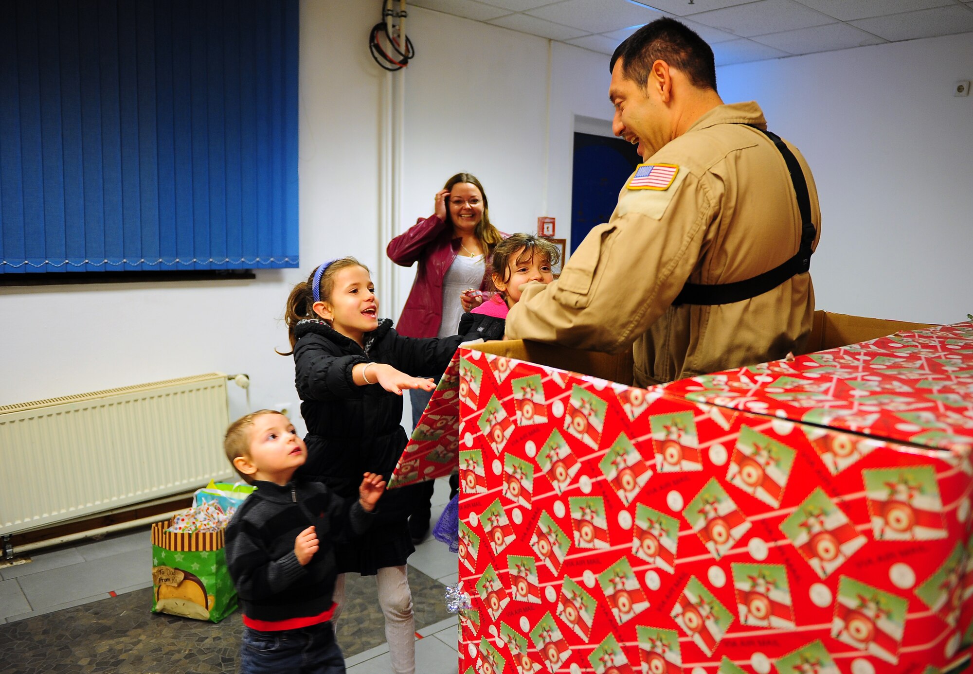 Staff Sgt. Richard Anderson, 37th Airlift Squadron loadmaster, bursts out of a gift-wrapped box surprising his daughters Rain and Faith, and son, James right before Christmas, Dec. 23, 2014 at Ramstein Air Base Germany. Anderson and his wife, Amy, discovered he would be returning home earlier than expected and decided to give their children the gift they were asking for; to spend the holidays together as a family. (U.S. Air Force photo/Staff Sgt. Kris Levasseur)