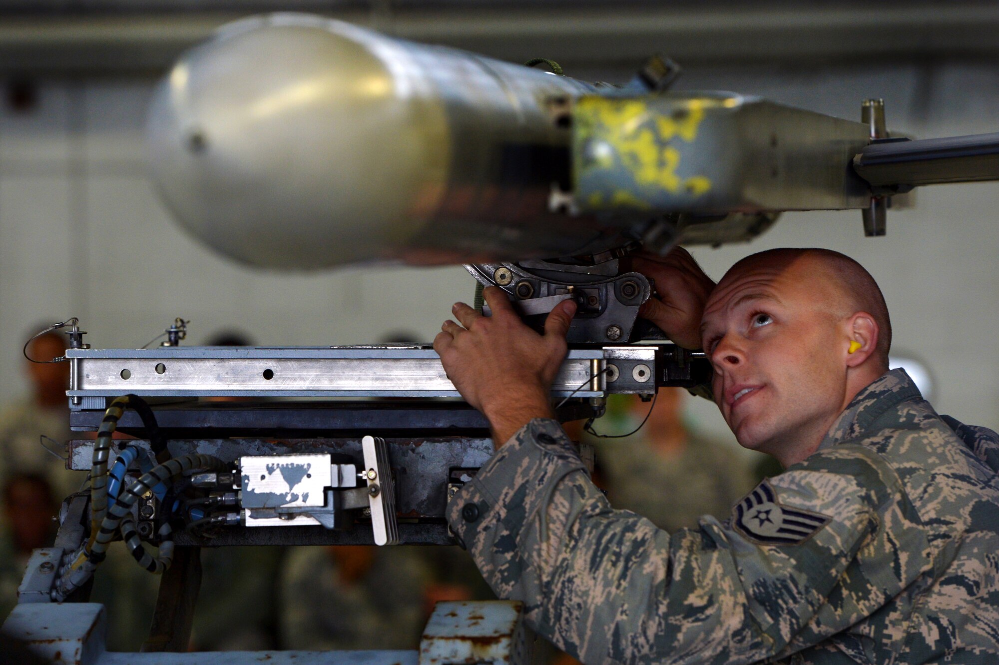 U.S. Air Force Staff Sgt. Robert Olsen, 20th Aircraft Maintenance Squadron weapons load crew member assigned to crew 79-10 “Tigers”, guides munitions into place on an F-16CM Fighting Falcon during a weapons load crew of the quarter competition at Shaw Air Force Base, S.C., Dec. 22, 2014. The LCOQ competition is designed to enhance Airmen’s skills while operating under pressure. (U.S. Air Force photo by Staff Sgt. Kenny Holston/Released)
