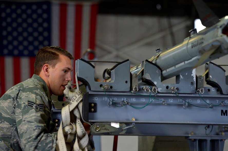 U.S. Air Force Senior Airman Nicolas Sampson, 20th Aircraft Maintenance Squadron weapons load crew member assigned to crew 55-07 “Shooters”, unstraps munitions in preparation to load them onto an F-16CM Fighting Falcon during a weapons load crew of the quarter competition at Shaw Air Force Base, S.C., Dec. 22, 2014. Sampson and his team loaded 4 weapons on to the aircraft in under 30 minutes while striving to win the competition. (U.S. Air Force photo by Staff Sgt. Kenny Holston/Released)