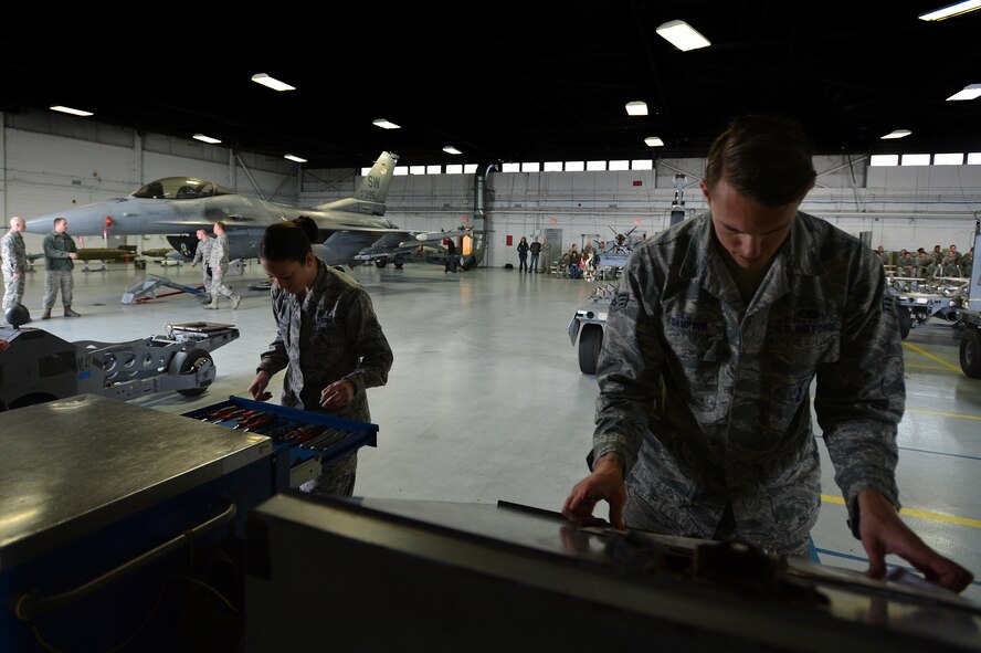 U.S. Air Force Airman 1st Class Victoria Baldwin-King, (left) and Senior Airman Nicolas Sampson, both 20th Aircraft Maintenance Squadron weapons load crew members assigned to crew 55-07 “Shooters”, situate their tools and review manuals during a weapons load crew of the quarter competition at Shaw Air Force Base, S.C., Dec. 22, 2014. Crew 55-07 worked together to load munitions onto an F-16CM Fighting Flacon in less than 30 minutes. (U.S. Air Force photo by Staff Sgt. Kenny Holston/Released)