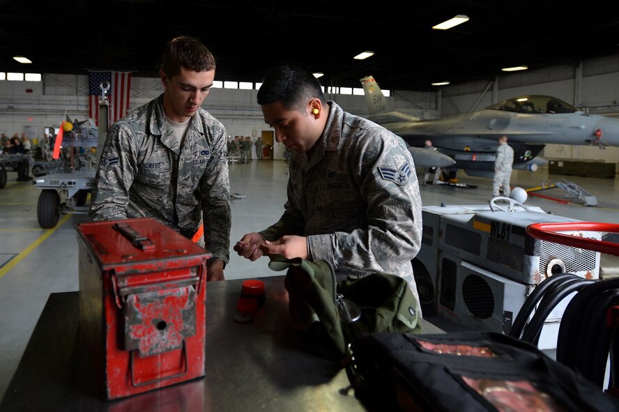 U.S. Air Force Airman 1st Class Cody Howard, (left) and Senior Airman Alexander Lopez, both 20th Aircraft Maintenance Squadron weapons load crew members assigned to crew 79-10 “Tigers”, situate their tools while competing in a weapons load crew of the quarter competition at Shaw Air Force Base, S.C., Dec. 22, 2014. Howard and Lopez worked alongside Staff Sgt. Robert Olsen, also 20th AMXS weapons load crew member, to quickly and accurately load munitions onto an F-16CM Fighting Falcon. (U.S. Air Force photo by Staff Sgt. Kenny Holston/Released)