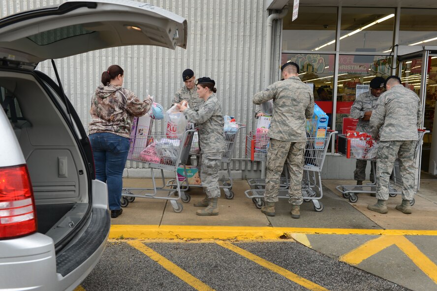 Airmen assigned to the 20th Security Forces Squadron lineup to load gifts into a vehicle during a “shop with a cop” event at Kmart in Sumter, S.C., Dec. 22, 2014. Members of the 20th SFS raised approximately $2,000 for more than 30 kids from the John K. Crosswell Home For Children to purchase gifts for themselves and their families. (U.S. Air Force photo by Senior Airman Jensen Stidham/Released)
