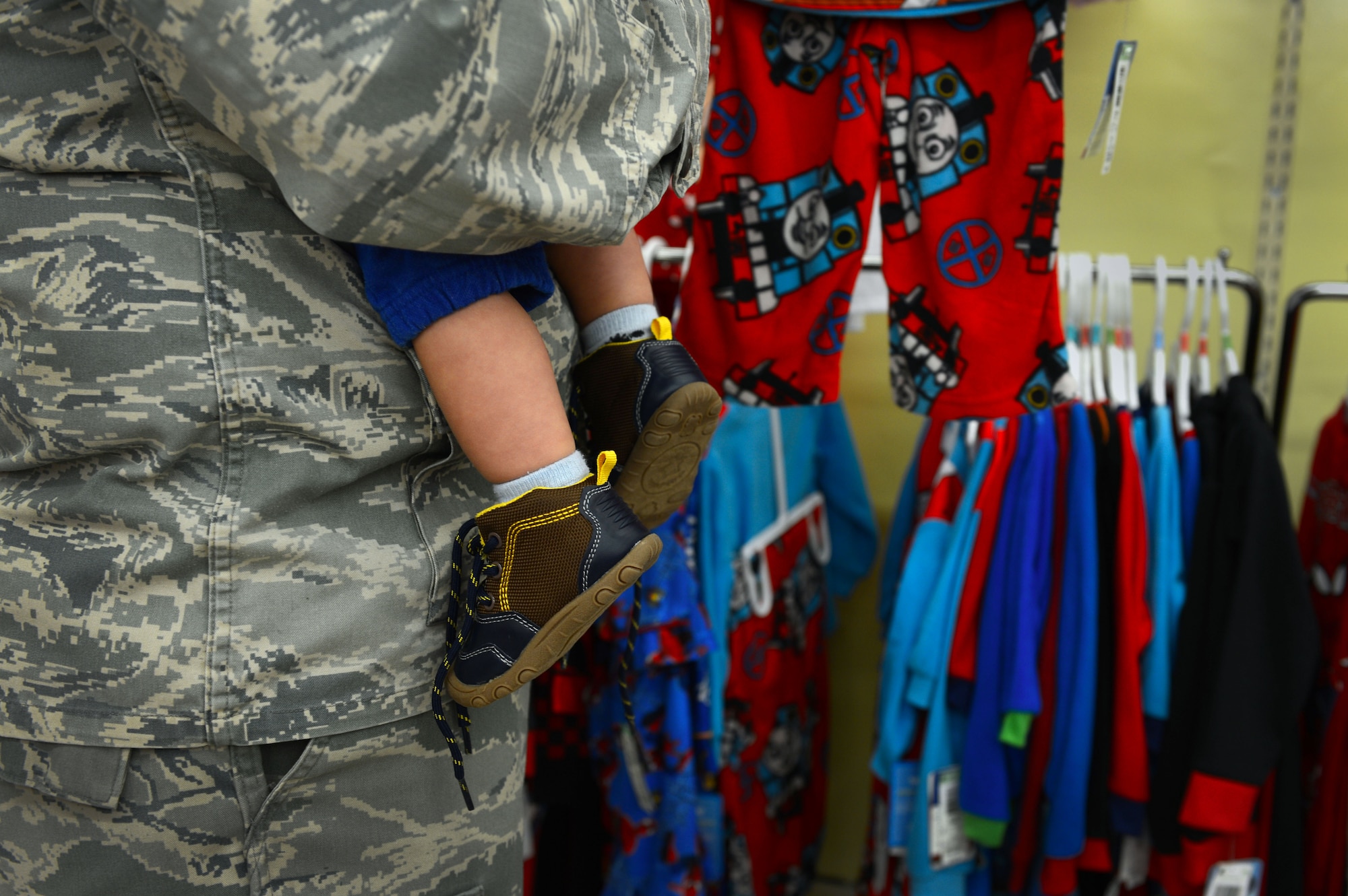An Airman assigned to the 20th Security Forces Squadron holds a child while looking at clothes during a “shop with a cop” event at Kmart in Sumter, S.C., Dec. 22, 2014. Approximately 50 Airmen walked around the store and assisted the more than 30 children as they picked out gifts to purchase with money raised by the 20th SFS. (U.S. Air Force photo by Senior Airman Jensen Stidham/Released) 