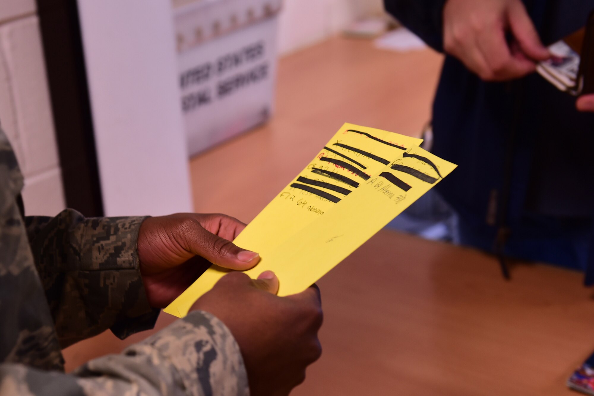 Airman Michael Wells, 422nd Communication Squadron postal technician, is verifying names on the yellow (package) notification cards to the customer’s identification cards, Dec. 2, 2014. The volume of mail increases 150-300% per post office during the holiday season, which can overwhelm the post office staff. (U.S. Air Force photo by Tech. Sgt. Chrissy Best)