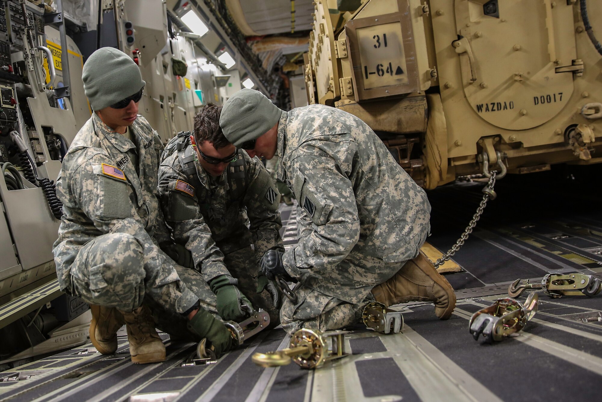 Soldiers from the U.S. Army’s 3rd Infantry Division stationed at Fort Stewart, Ga. attach a tie-down chain to secure an M2A3 Bradley Fighting Vehicles in a C-17 Globemaster III Dec. 11, 2014 at Hunter Army Airfield, Ga. The cargo movement was part of a two-day exercise which integrated C-17 air and ground crew training for 315th Airlift Wing Airmen stationed at Joint Base Charleston, S.C. as well as Soldiers from one of the 3rd Infantry Division’s Immediate Ready Companies who can deploy within 22 hours. Four C-17’s were used during the exercise to deploy and redeploy two Abrams M1A2 tanks, an M88 recovery vehicle and two M2A3 Bradley Fighting Vehicles. (U.S. Air Force photo by Tech. Sgt. Shane Ellis)