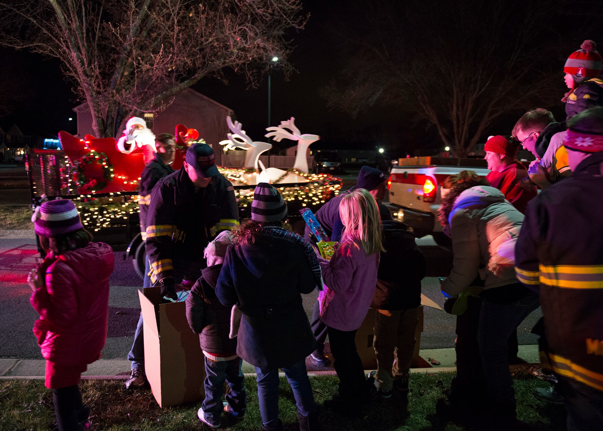 Joint Base McGuire-Dix-Lakehurst Fire Fighters hand out candy canes and small toys to the local children as Santa rides by them wishing everyone a Merry Christmas, Dec. 18, 2014. The JB MDL Fire Department Candy Cane Run is an annual event where fire fighters hand out candy canes to spread holiday cheer and raise morale. (U.S. Air Force photo by Airman 1st Class Joshua King/Released)