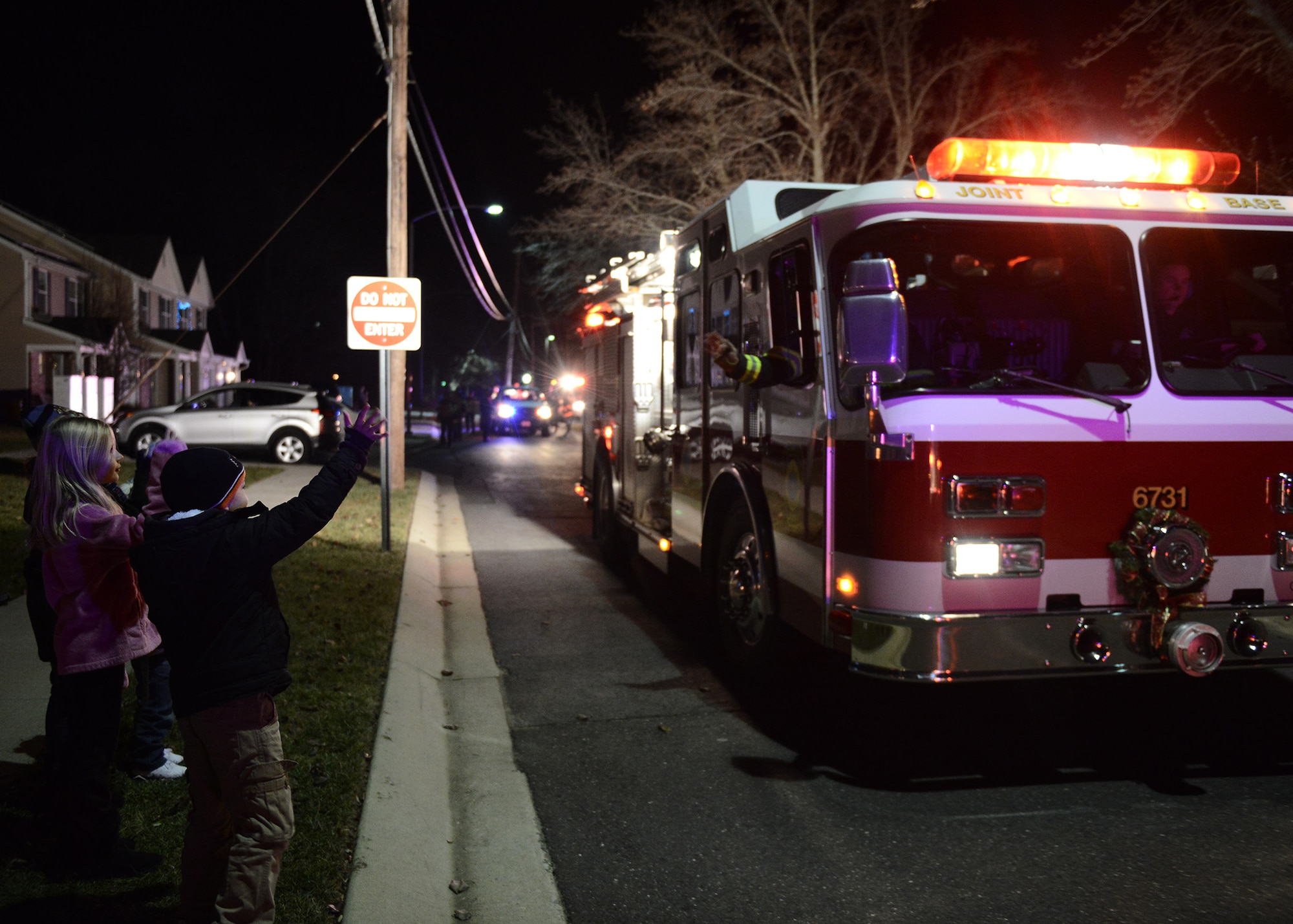 A Joint Base McGuire-Dix-Lakehurst, N.J., fire fighter waves to local children during a parade to hand out candy canes to children, Dec. 18, 2014. The JB MDL Fire Department Candy Cane Run is an annual event where fire fighters hand out candy canes to spread holiday cheer and raise morale. (U.S. Air Force photo by Airman 1st Class Joshua King/Released)