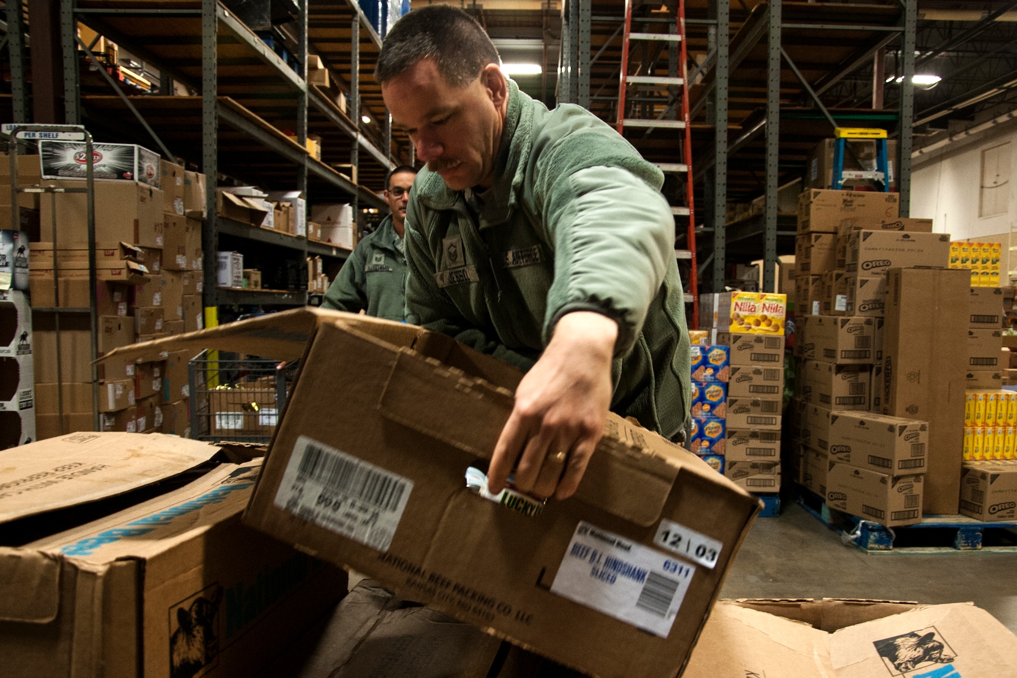 GOODFELLOW AIR FORCE BASE, Texas – Master Sgt. Matthew A. Jessel, 17th Communications Squadron information operations section chief, places a box full of food onto a cart during Operation Warmheart at the commissary warehouse Dec. 23. Volunteers helped package 140 boxes for members of Team Goodfellow. (U.S. Air Force photo/ Airman 1st Class Scott Jackson)